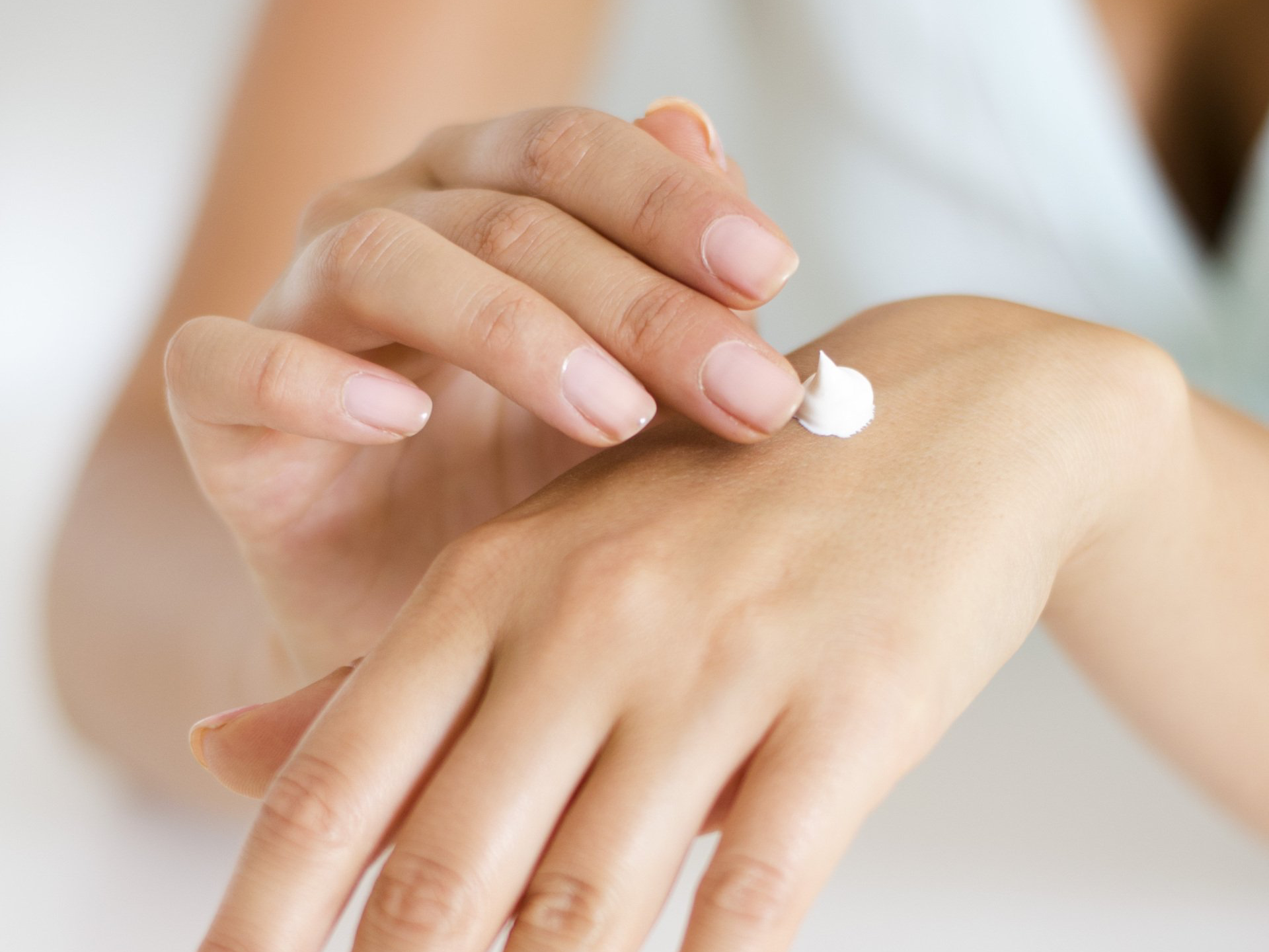 A woman is applying lotion to her hand.