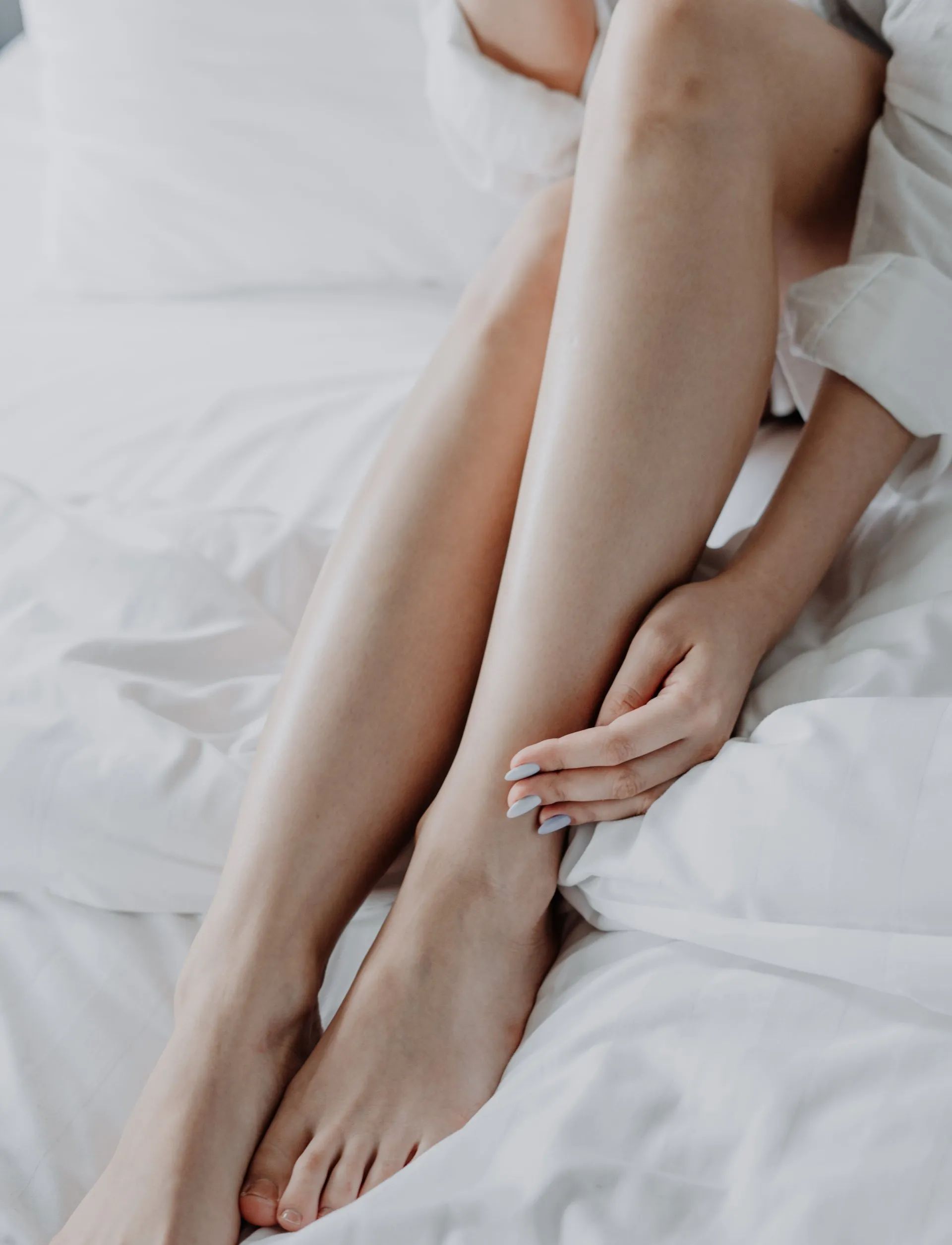 A woman is sitting on a bed with her legs crossed.