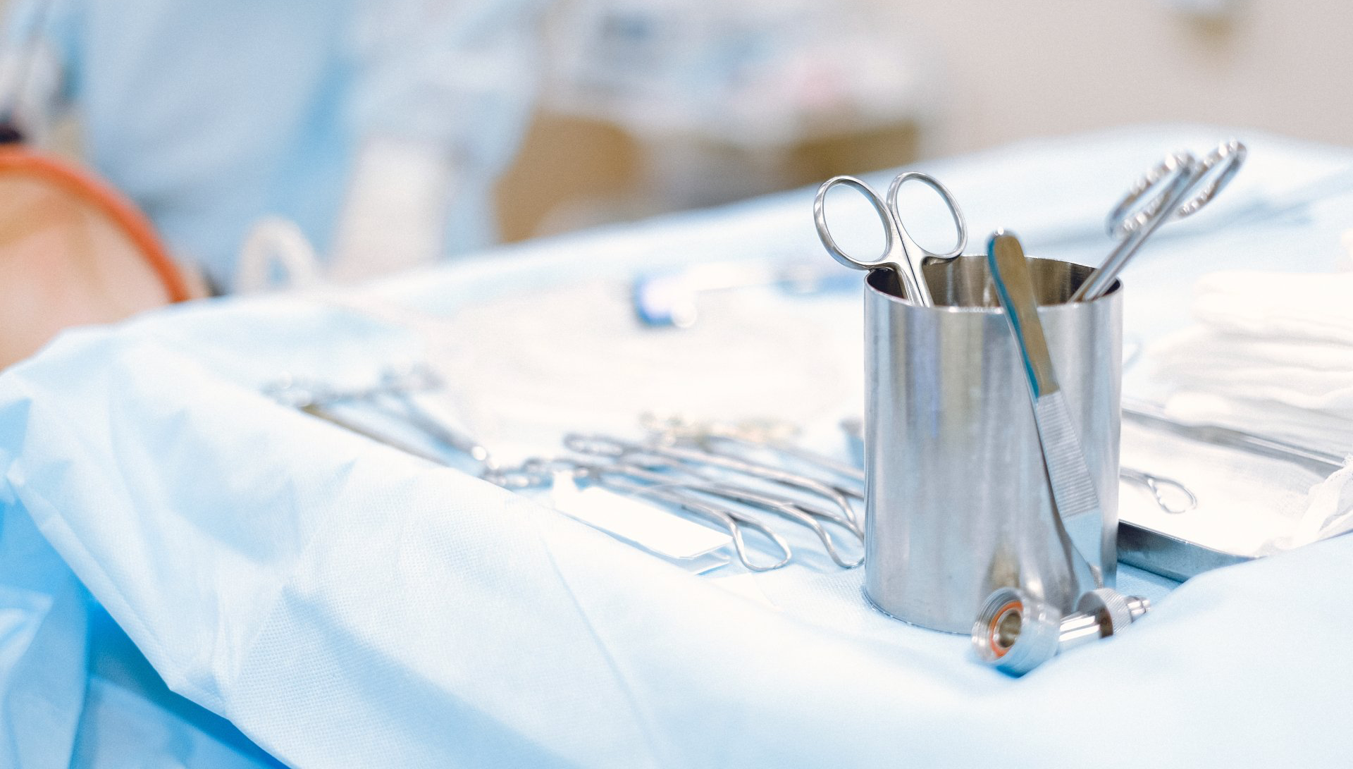 A stainless steel container filled with surgical instruments is sitting on a table.