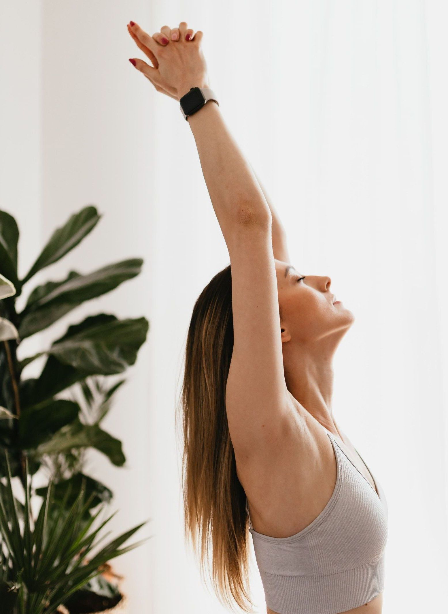 A woman is standing in a yoga pose with her arms in the air.