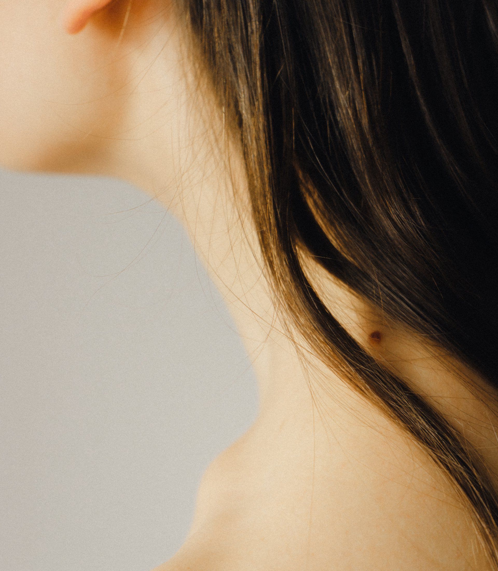 A close up of a woman 's neck with a mole