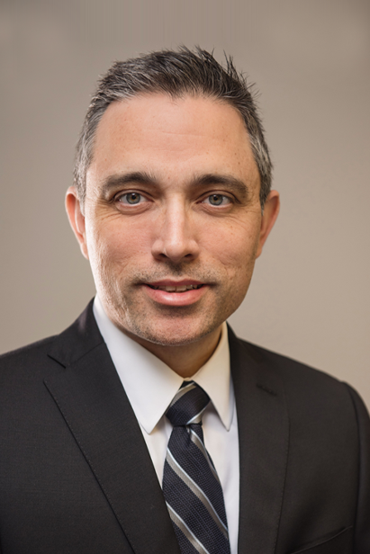 A woman wearing glasses and a white shirt is smiling for the camera.