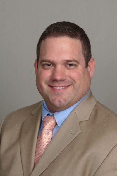 A man wearing glasses is sitting in front of a laptop computer.