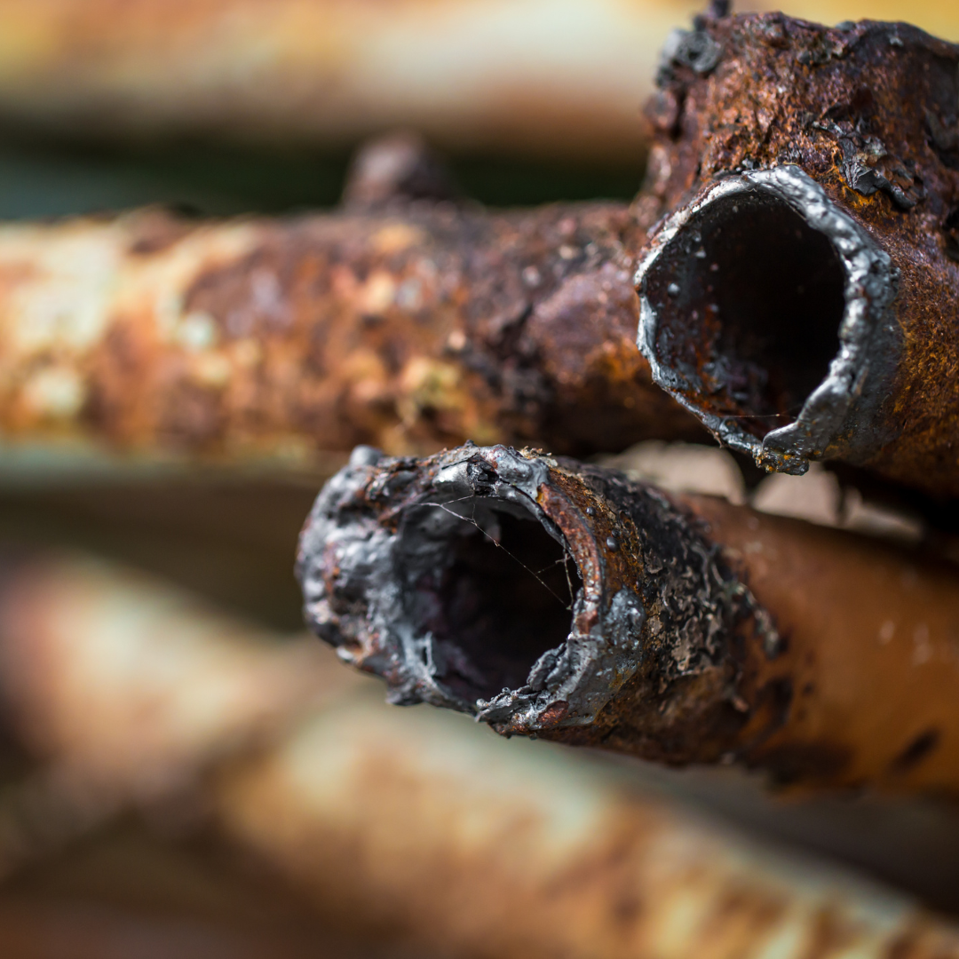 A close up of two rusty pipes stacked on top of each other.