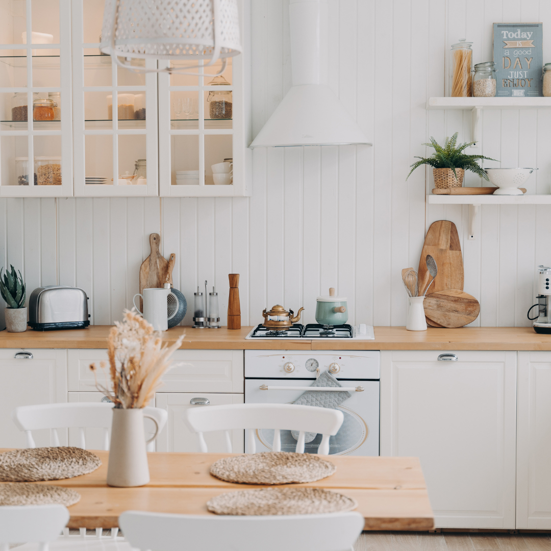 A kitchen with white cabinets and a wooden table and chairs.
