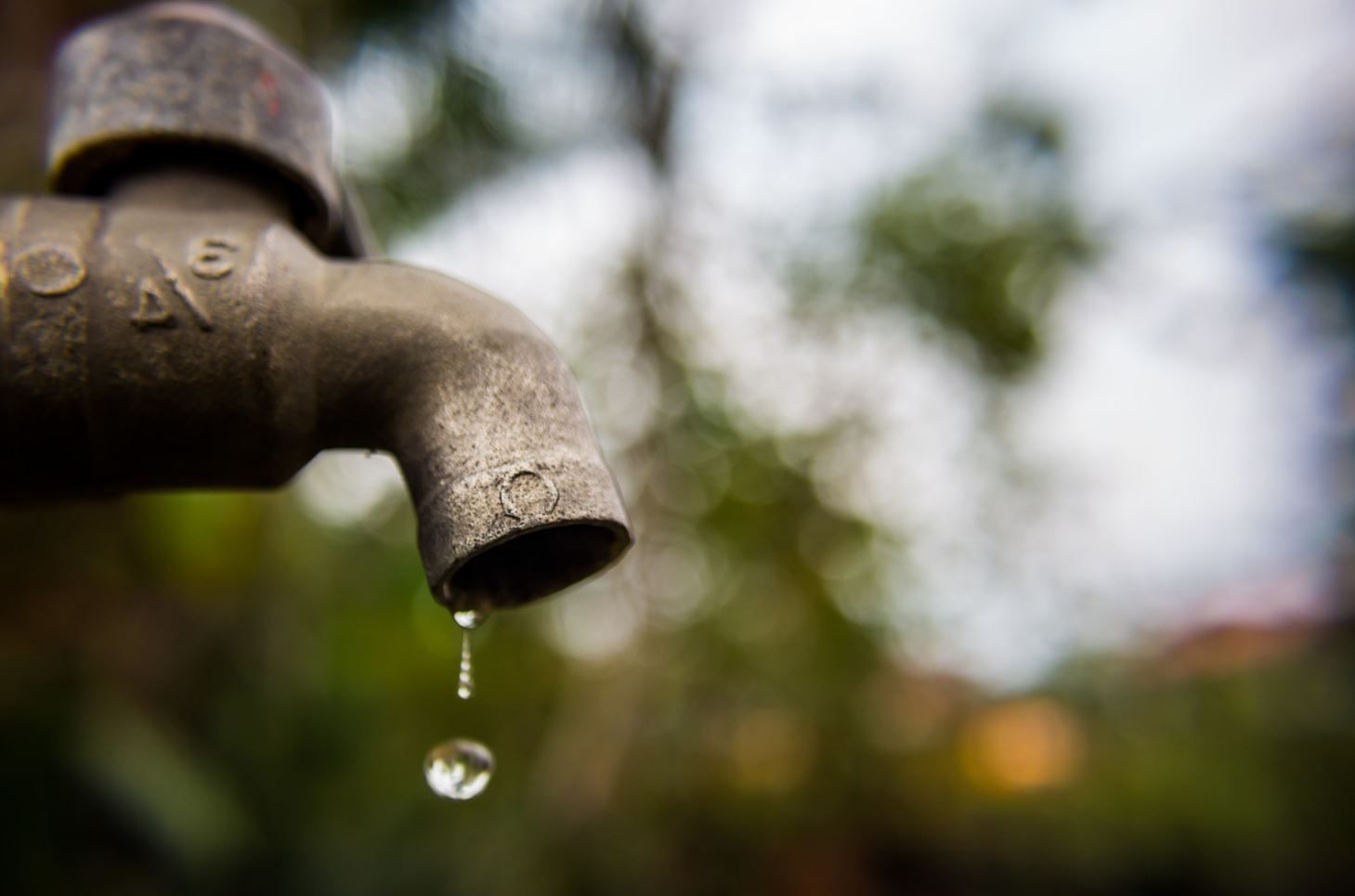 A close up of a water faucet with a drop of water coming out of it.