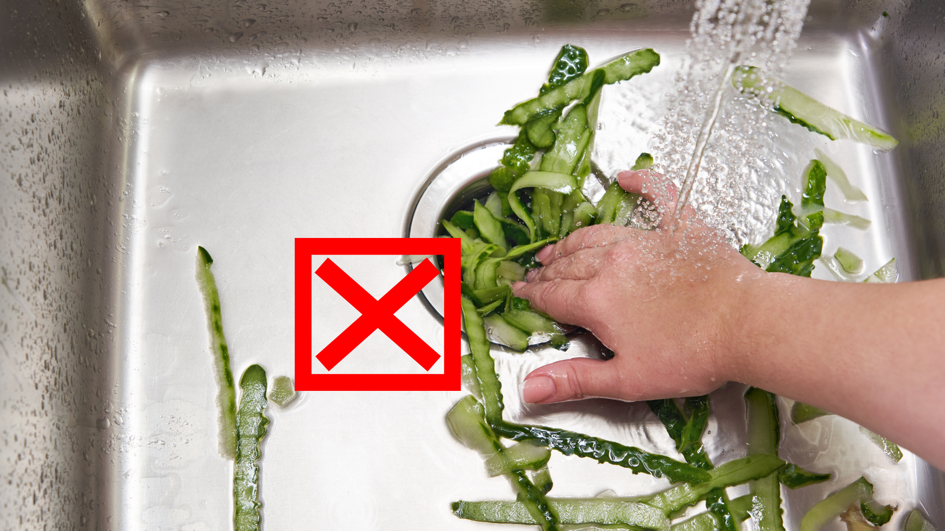 A person is washing vegetables in a sink with an x in the corner.
