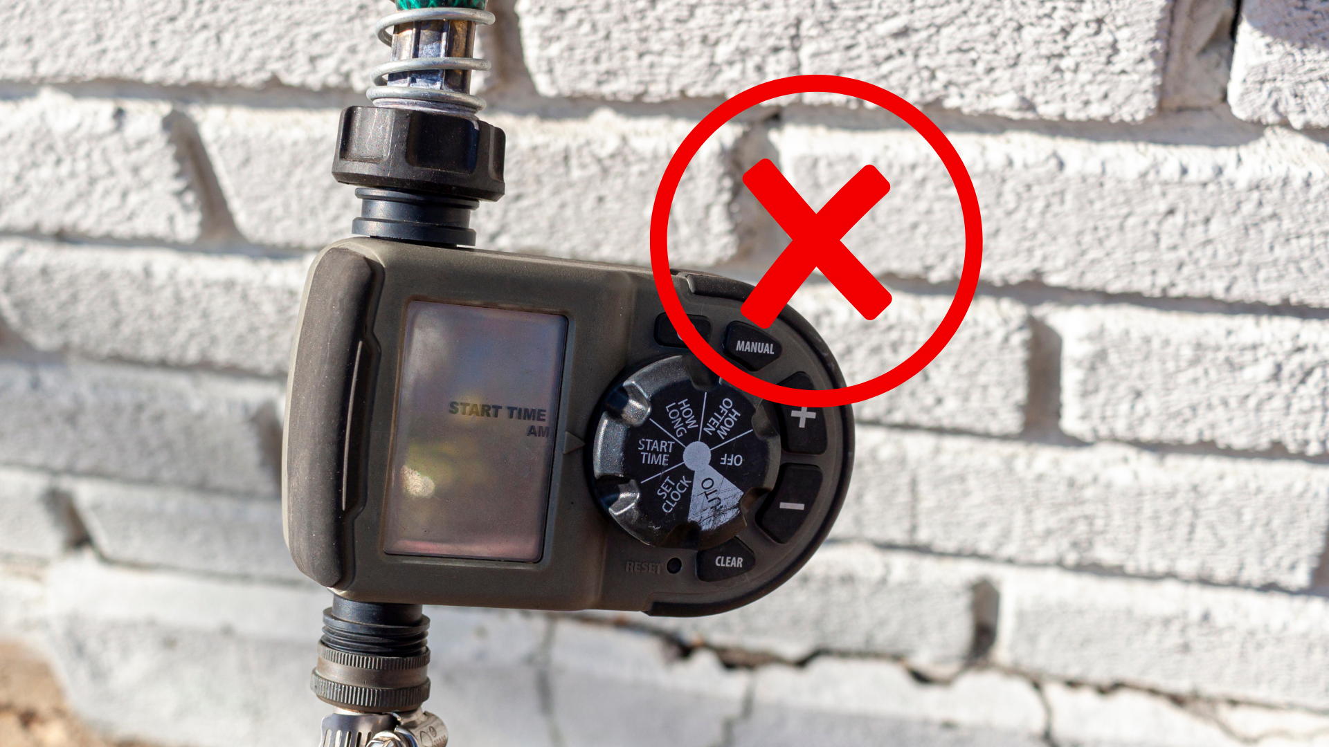A hose timer is attached to a brick wall with an x in the middle.