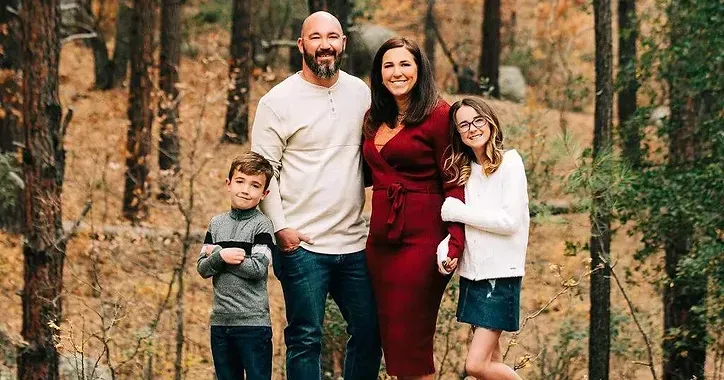 A family is posing for a picture in the woods.