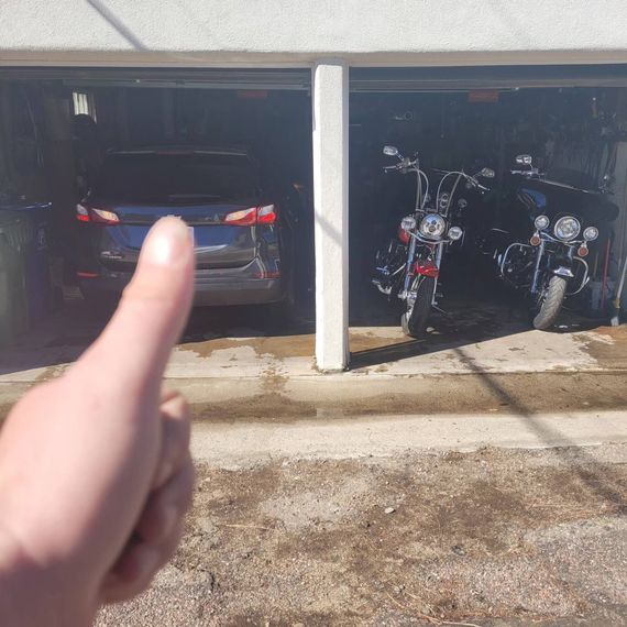 A person is pointing at two motorcycles parked in a garage