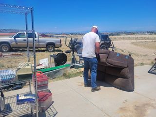 A man is standing next to a couch in front of a truck.