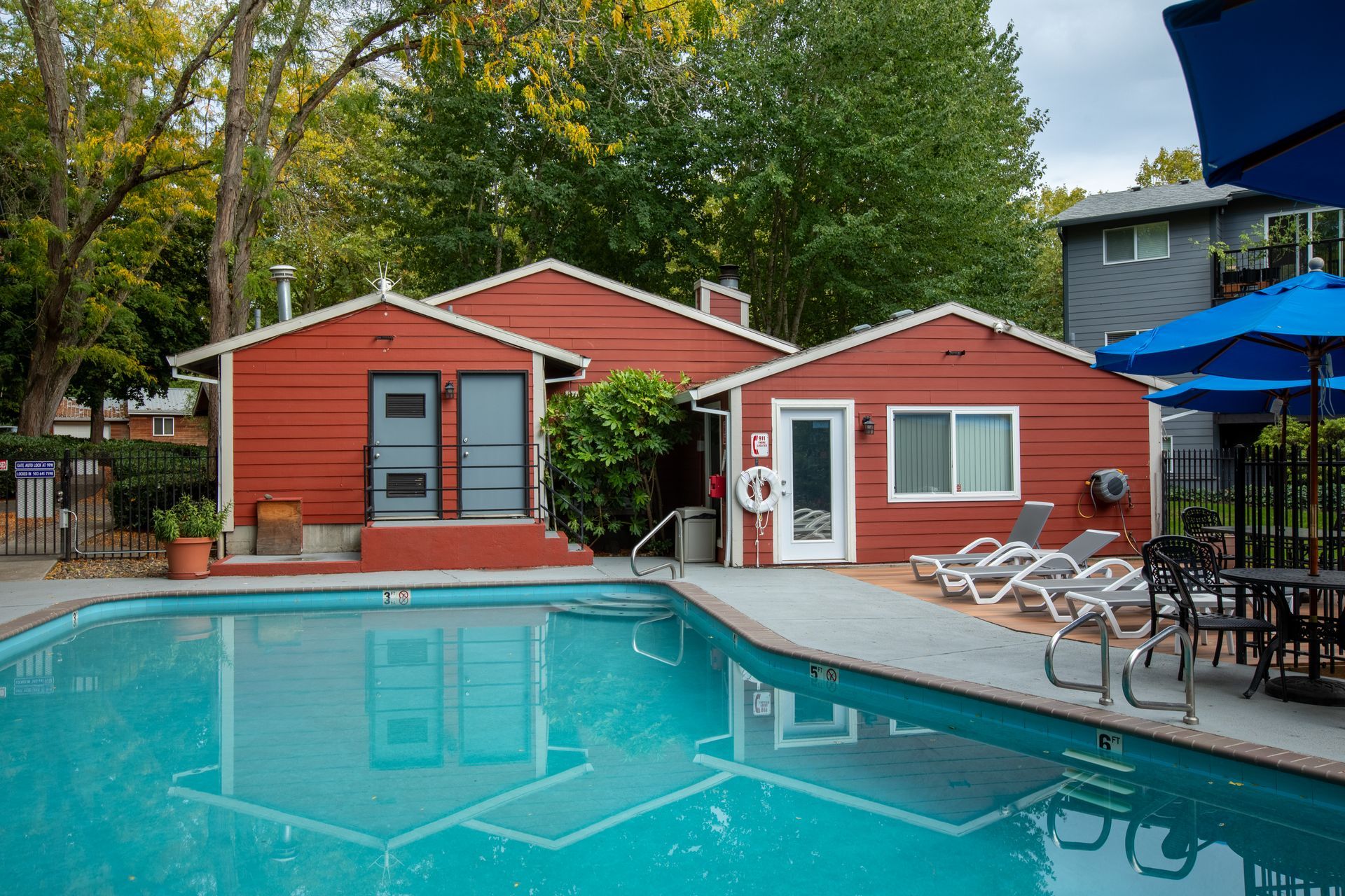 Red buildings surround a turquoise pool with lounge chairs and tables.