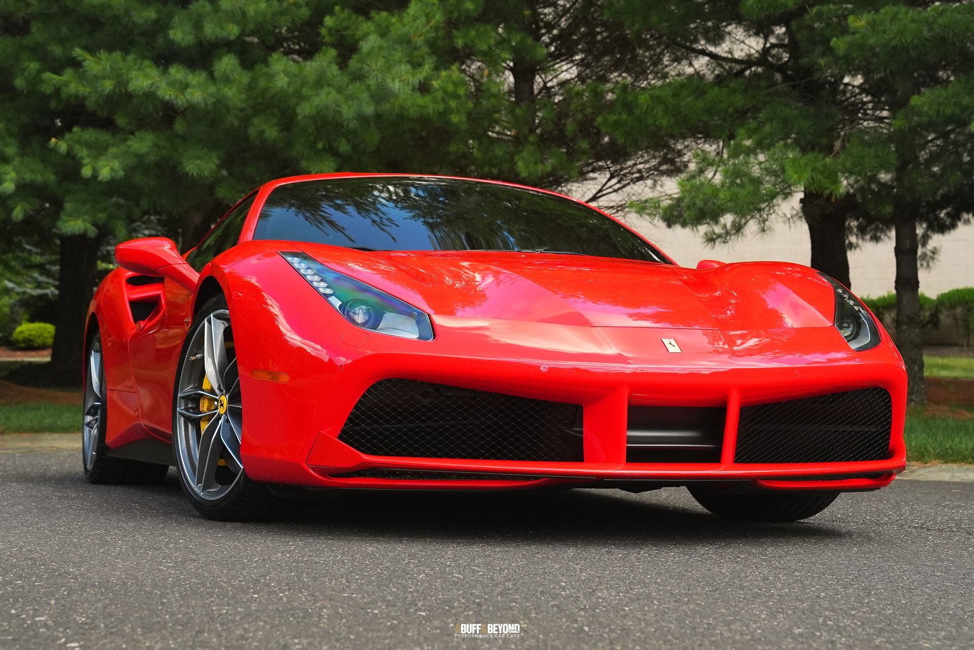 A red ferrari 488 spider is parked on the side of the road.