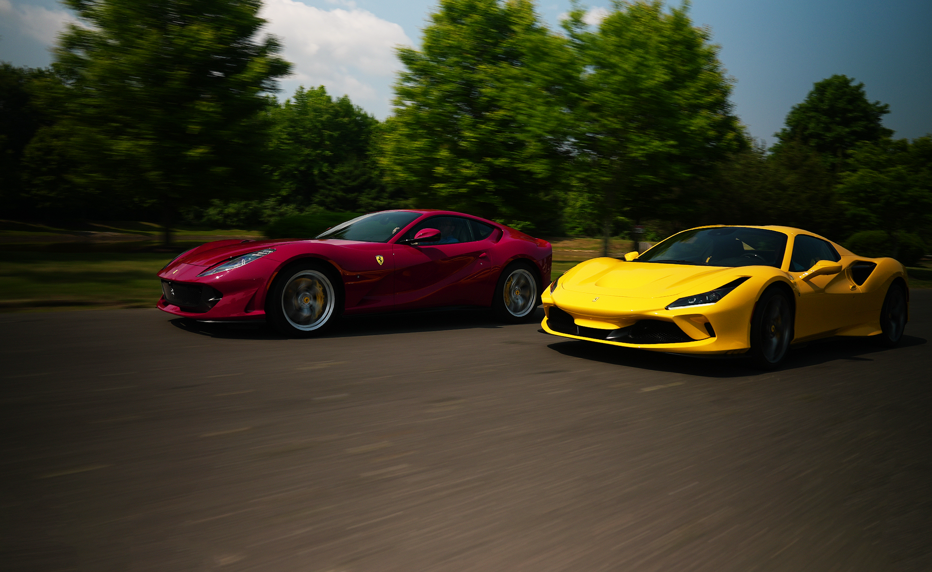 A red ferrari and a yellow ferrari are parked next to each other on a road.