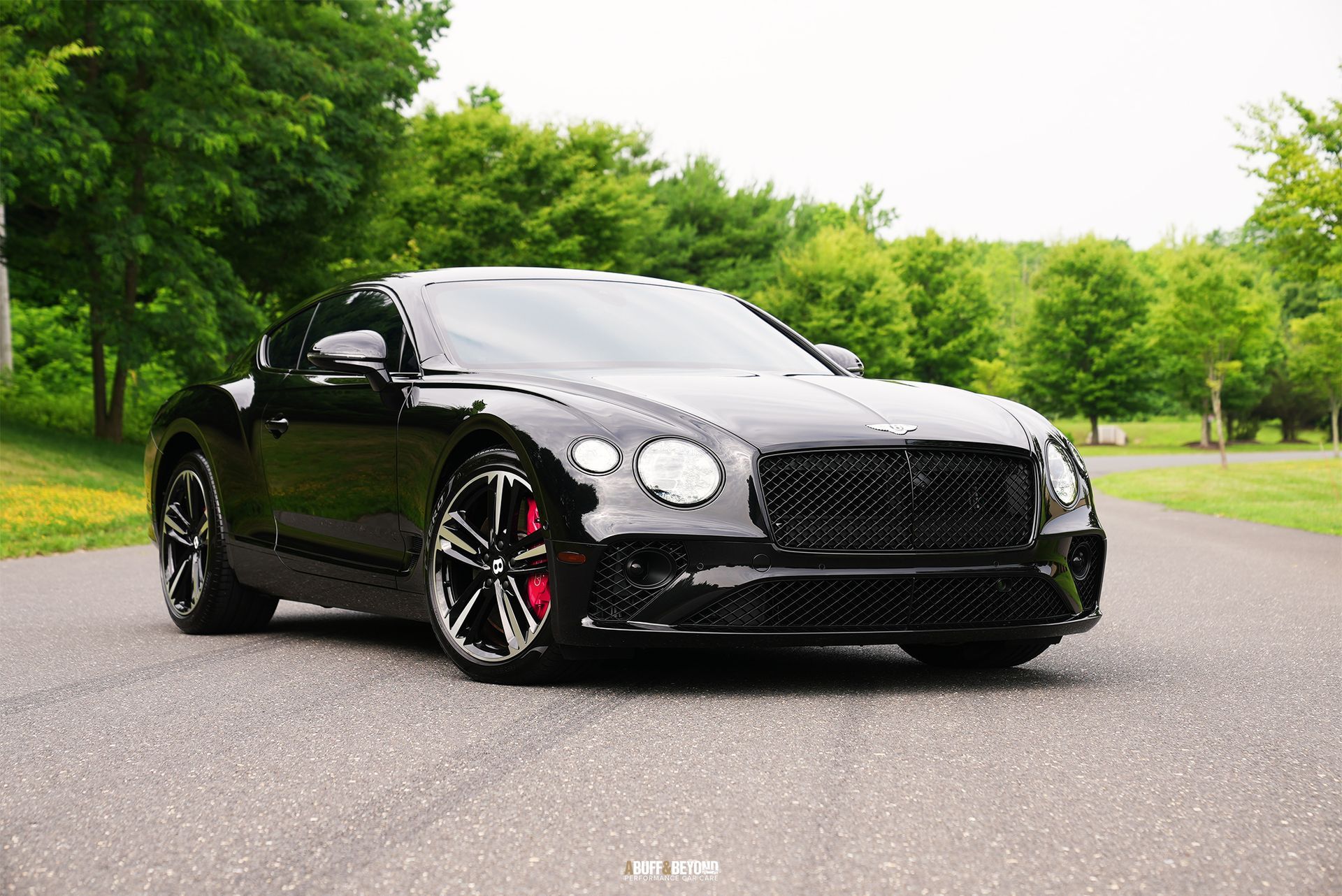 A black bentley continental gt is parked on the side of the road.