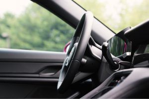 A close up of a car steering wheel with trees in the background