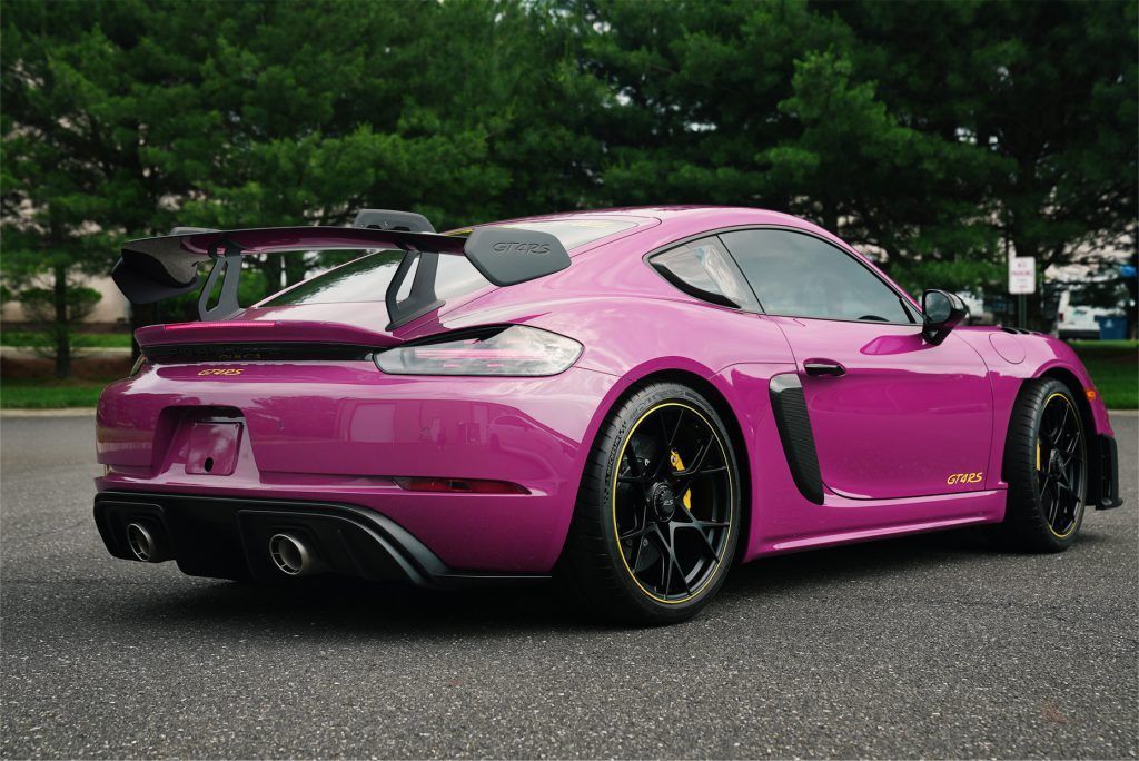 A pink porsche 911 gt2 rs is parked in a parking lot.
