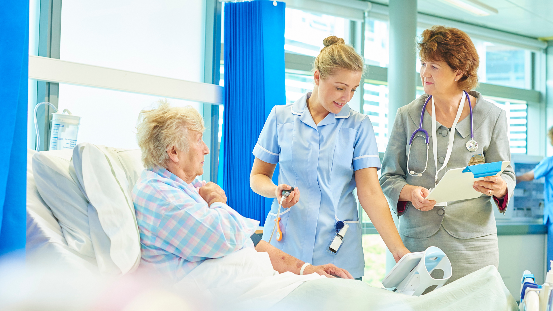 Nurse taking patient's blood pressure; doctor looks on in a hospital room.