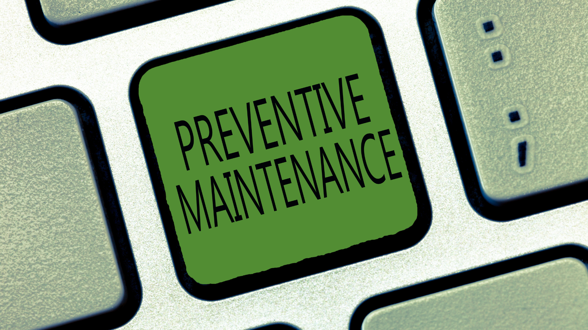 A keyboard with a green button that says preventive maintenance