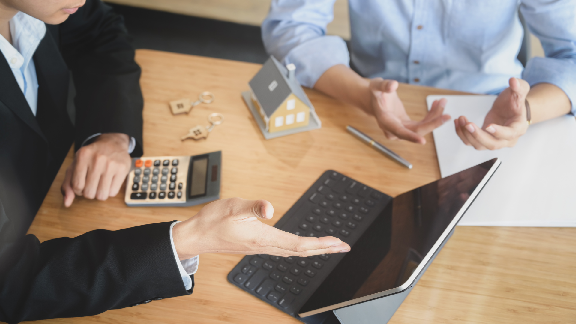 Two people are sitting at a table with a laptop and a calculator.