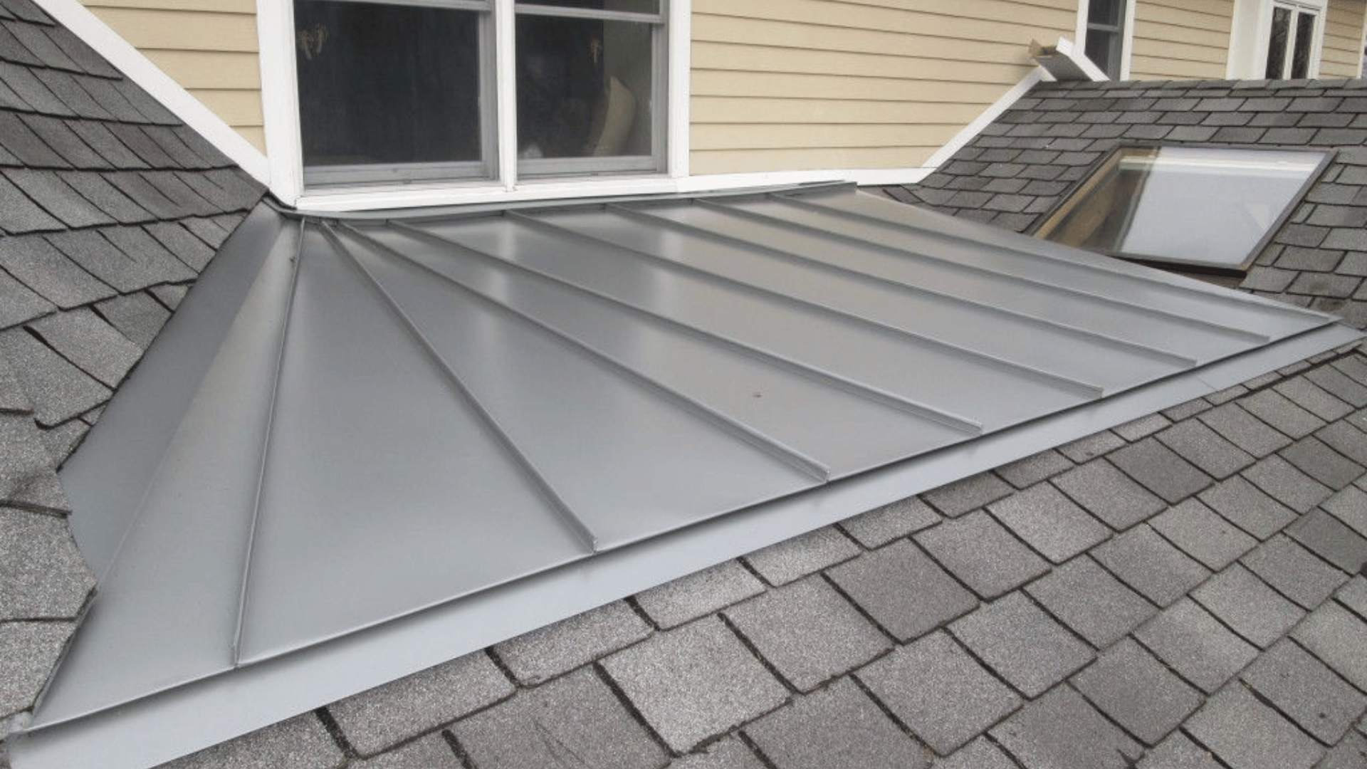 A close up of a roof with shingles and a skylight