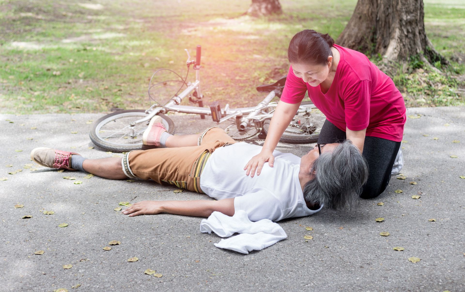 A man is helping a woman who is laying on the ground.