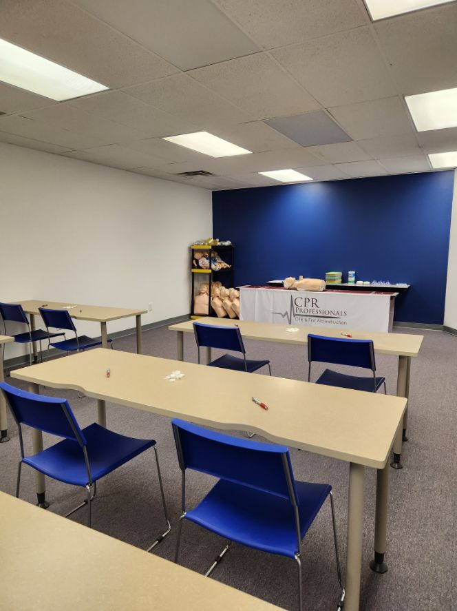 A classroom with tables and chairs and a blue wall