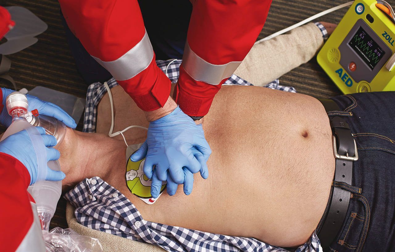 A man is laying on the floor with a aed machine in the background.