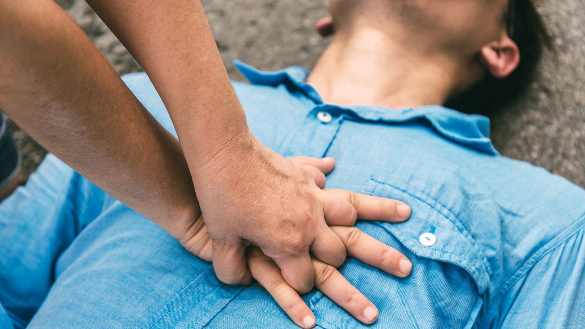 A man is laying on the ground with his hands on his chest.