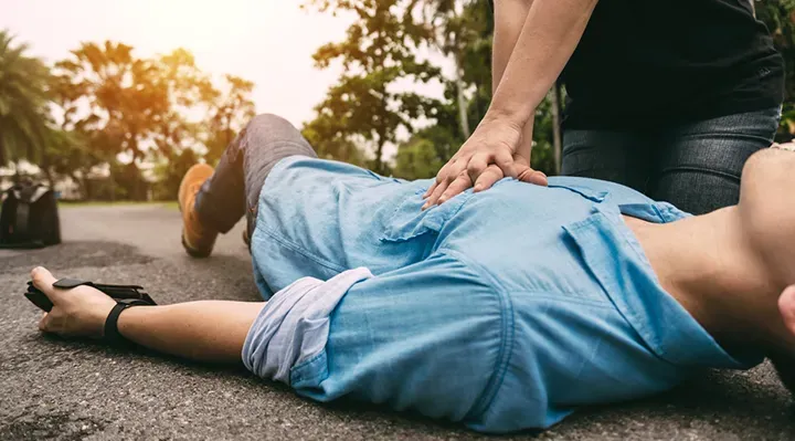 A woman is laying on the ground with a heart attack.