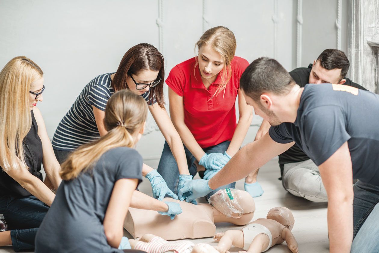 A group of people are practicing first aid on a mannequin.
