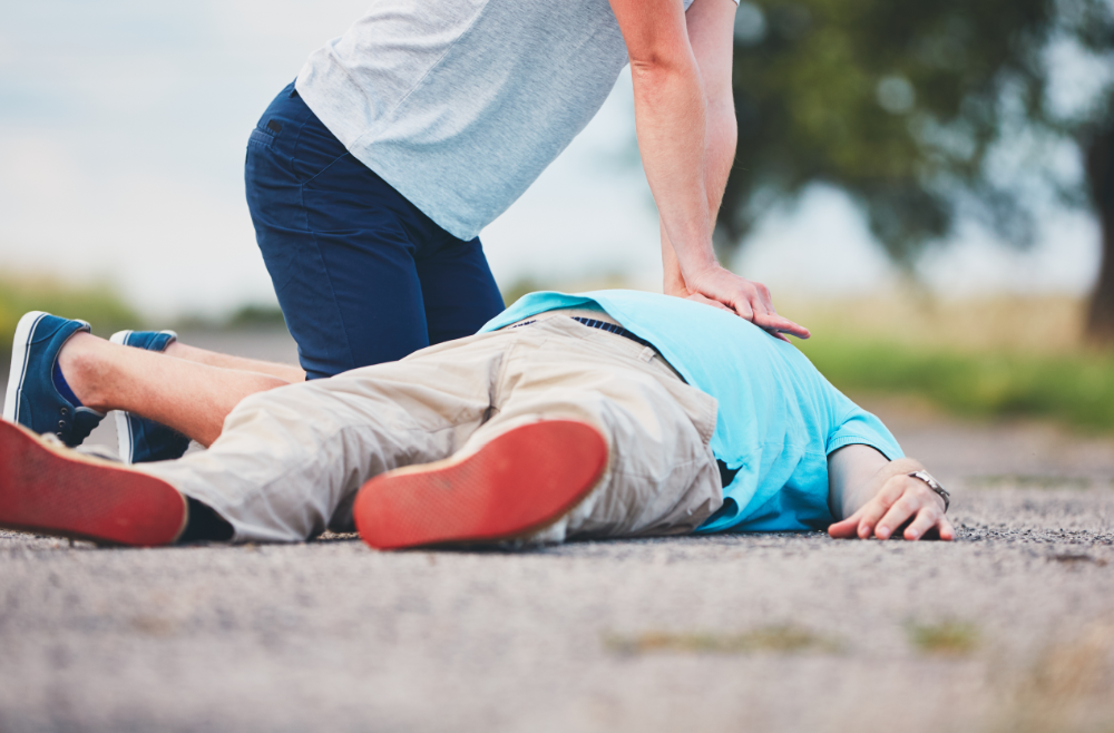A man is kneeling down to help a woman who is laying on the floor.