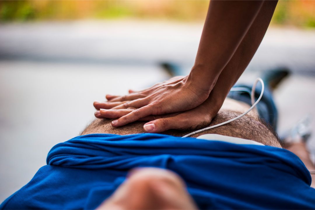 A person performing CPR on another individual lying on their back.