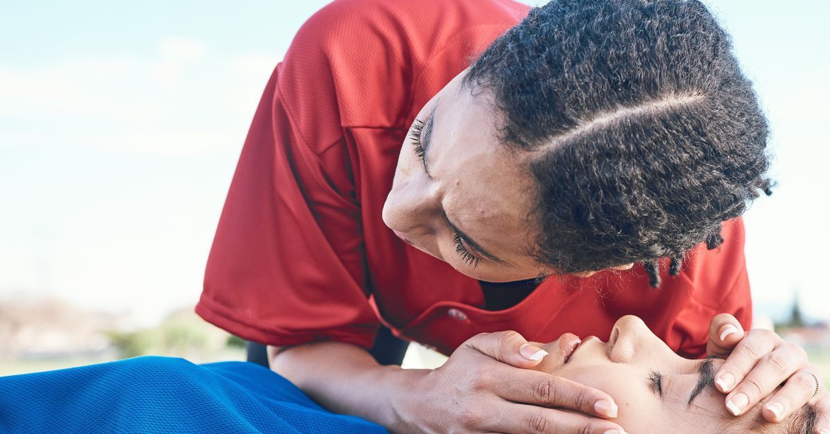 A woman in a red shirt is giving a child a heart massage.