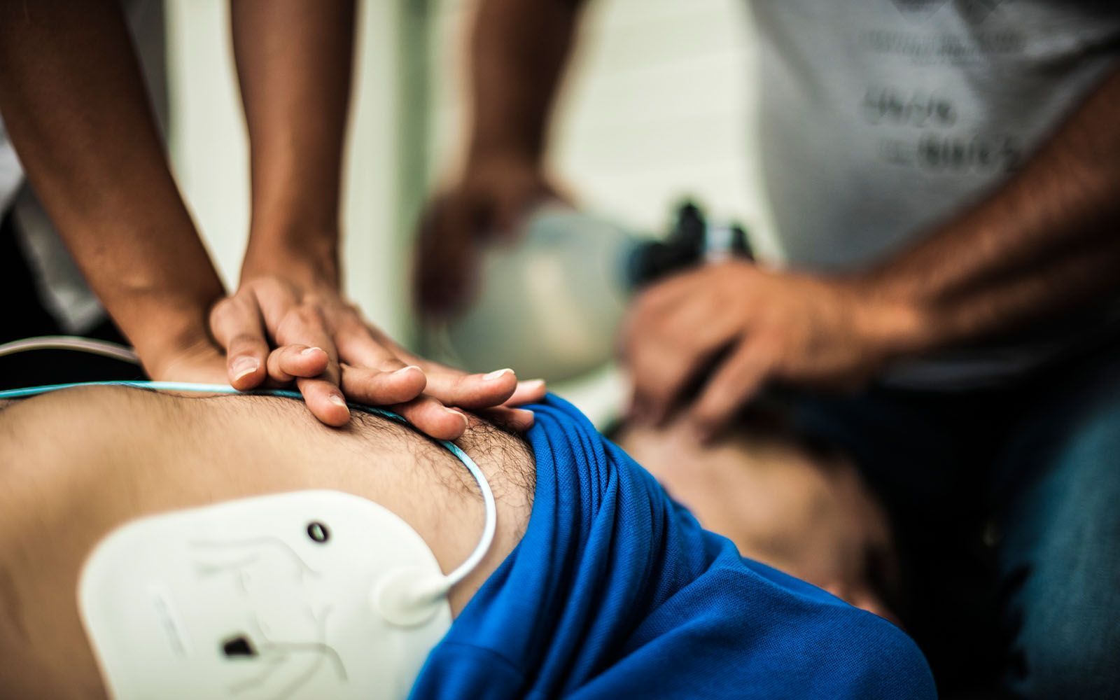 A man is laying on the floor with a defibrillator on his chest.
