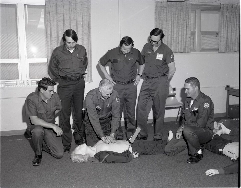 A group of men are kneeling around a man laying on the floor