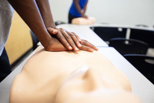 A person is putting their hands on a mannequin 's chest