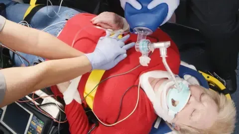 A man is laying on a stretcher in an ambulance with an oxygen mask on his face.