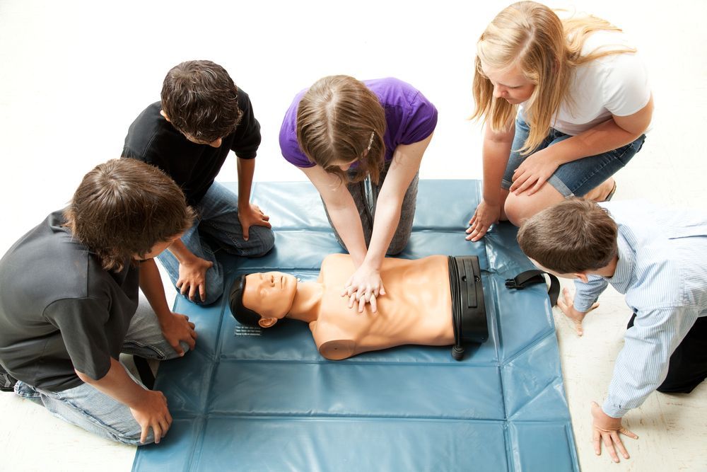 A group of people are practicing first aid on a mannequin.