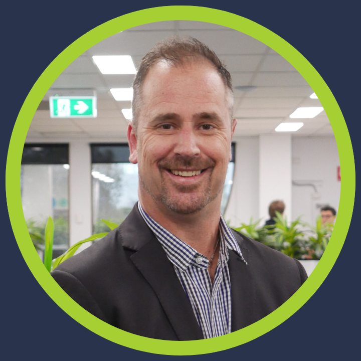 A man in a suit and white shirt is smiling in a green circle.