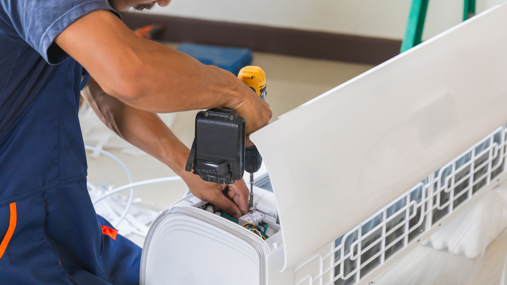 Worker using a drill to repair a white appliance or furniture piece indoors