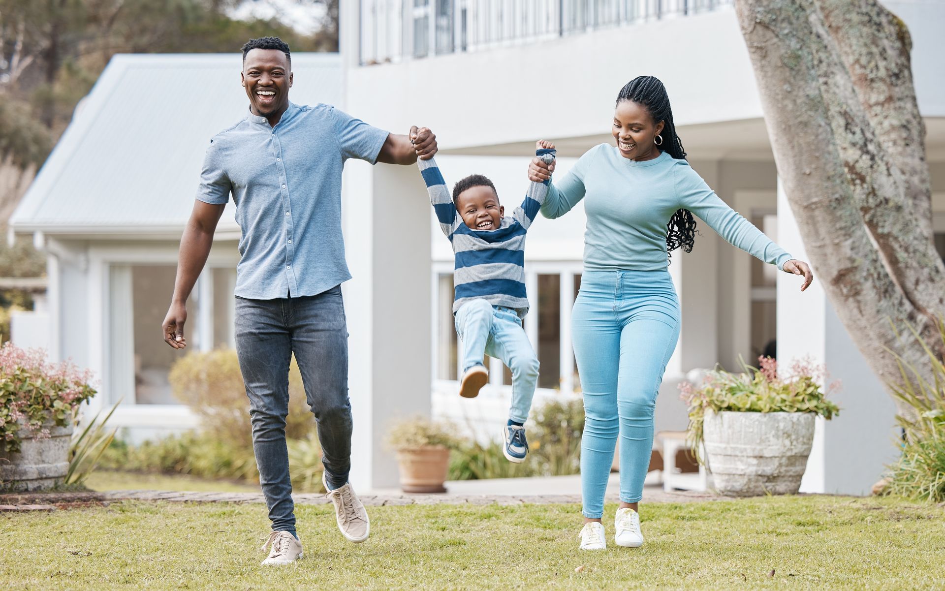 A family is walking in front of their house holding hands.