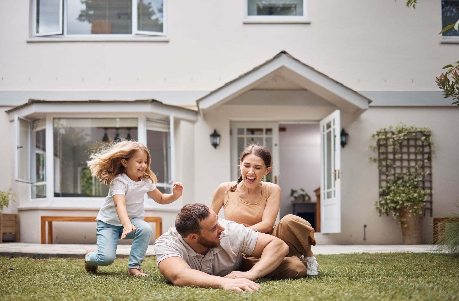 A family is playing in the grass in front of their house.