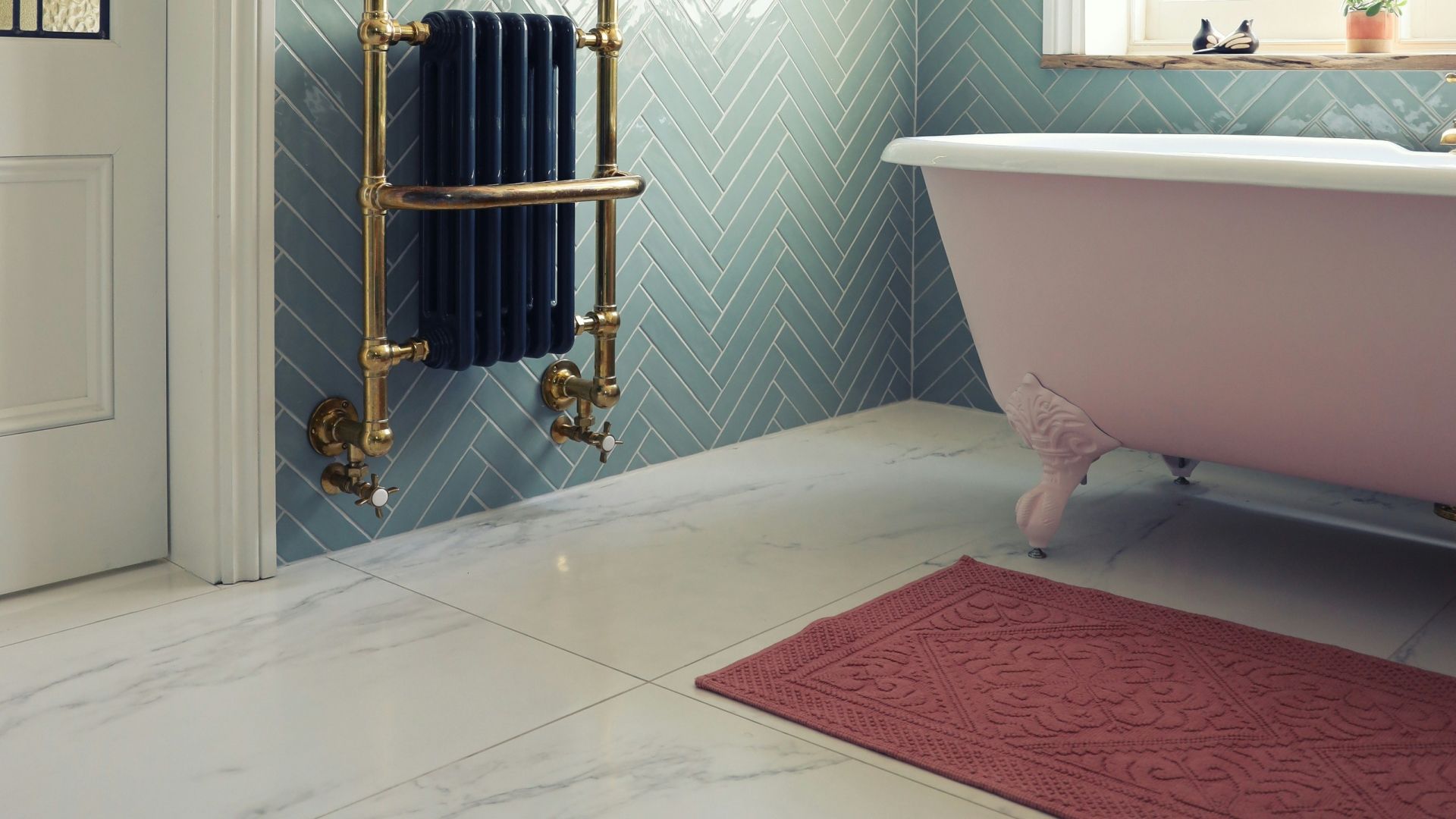 a bathroom with a pink bathtub , a towel rack , and a rug .