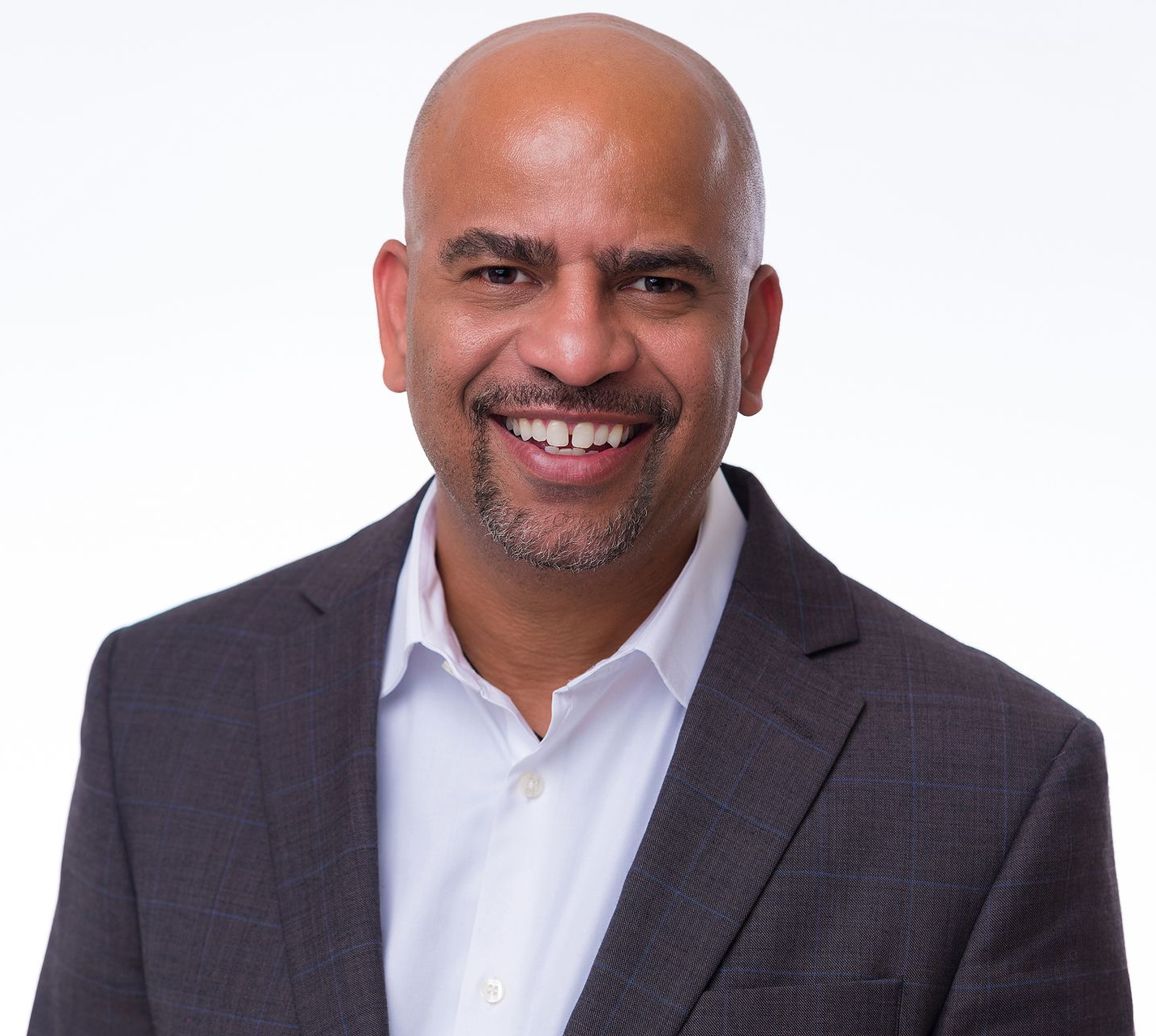 A bald man wearing glasses and a suit is looking at the camera in a black and white photo.