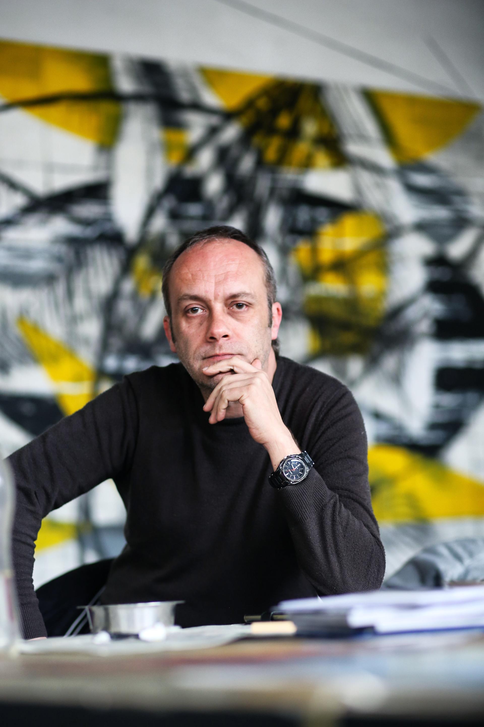 A man is sitting at a desk with his hand on his chin.