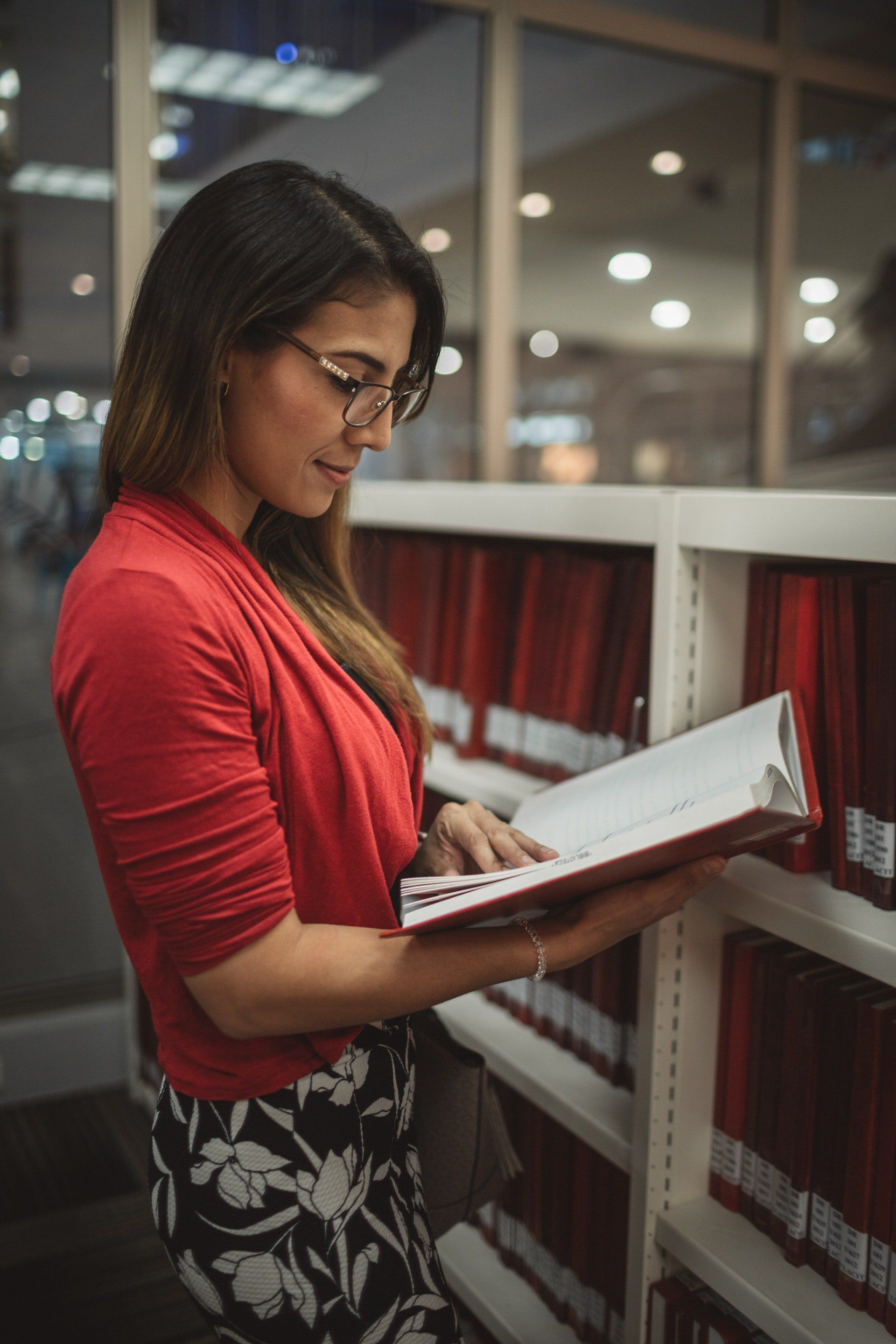 A woman is reading a book in a library.