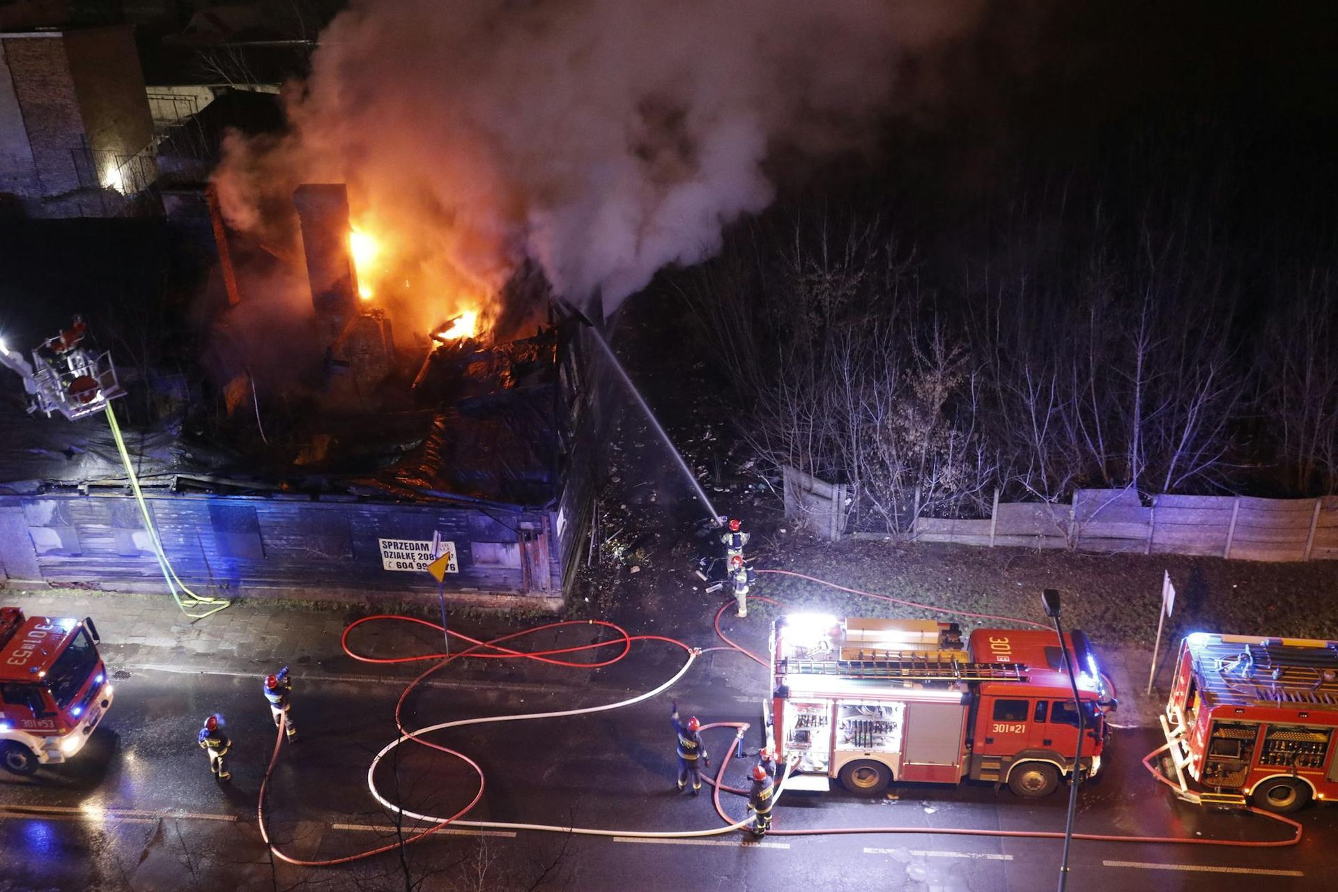 A fire truck is spraying water on a fire at night.