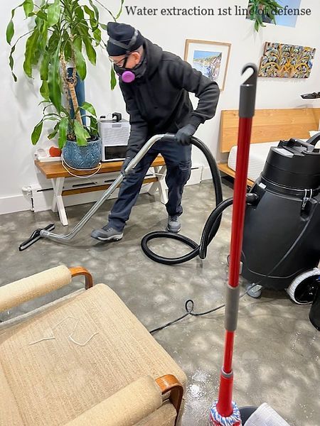 A man wearing a mask is using a vacuum cleaner to clean a room.