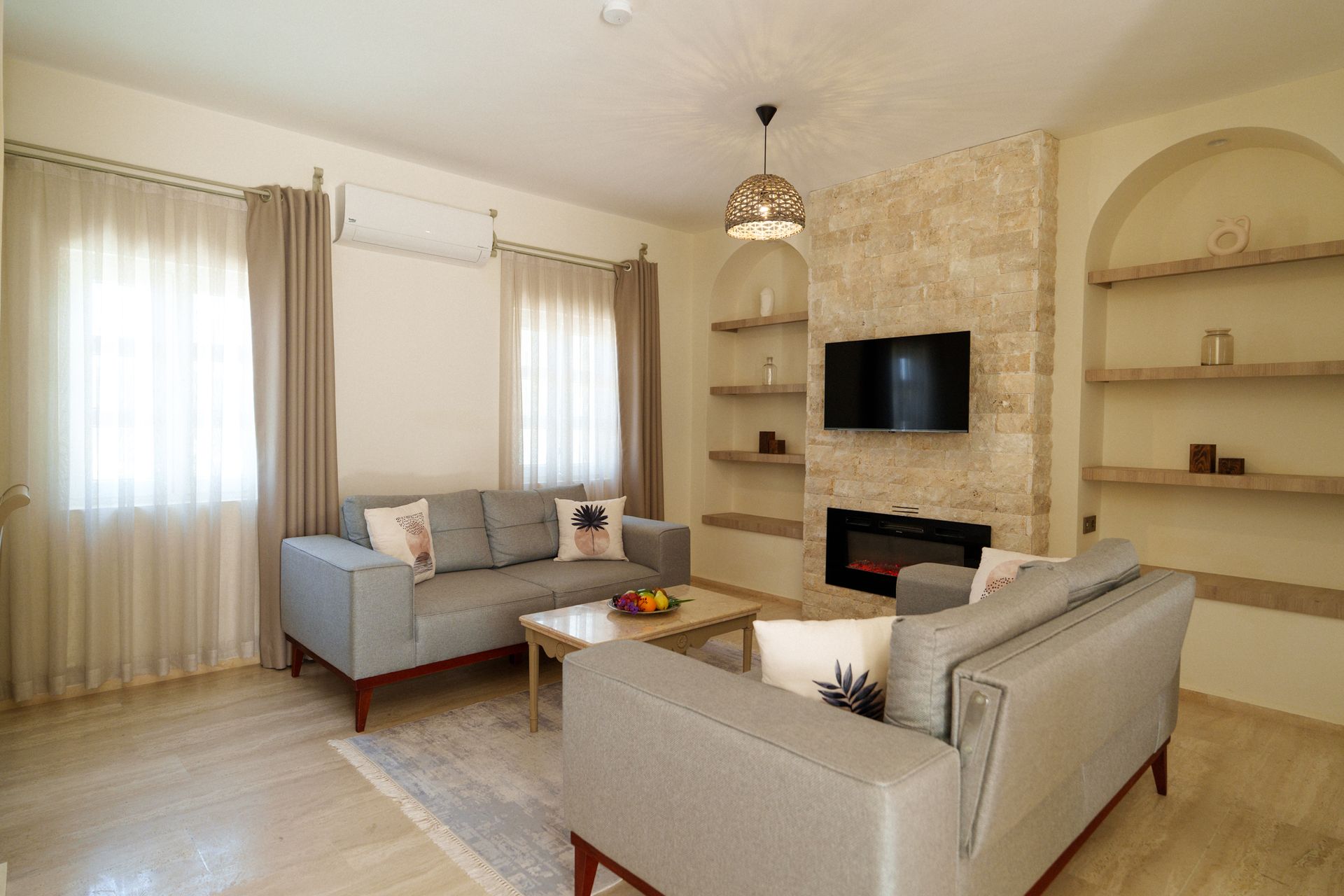 Manzara Boutique Hotel | Bright living room with beige sofas, fireplace, and large windows with sheer curtains